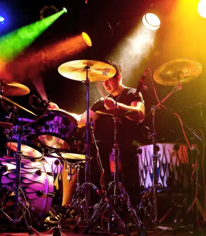 action photo of man playing the drums, with dramatic stage lighting